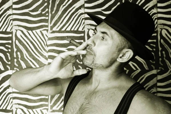 Macho in een vilten hoed en een sigaar in de handen van een foto gemaakt in zwart-wit — Stockfoto