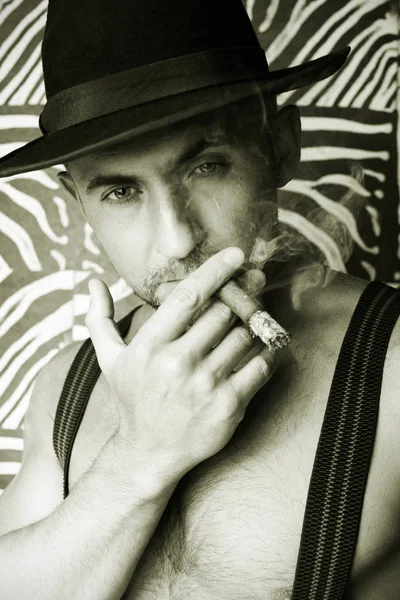 Macho en un sombrero de fieltro y un puro en las manos de una foto hecha en blanco y negro —  Fotos de Stock
