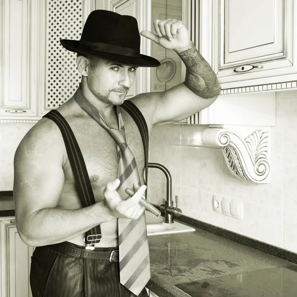 A muscular cowboy in a felt hat and a cigar in his hands in black and white — Stock Photo, Image