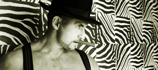 A muscular cowboy in a felt hat and a cigar in his hands in black and white — Stock Photo, Image