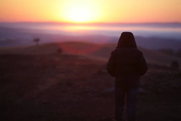 Stark anda flicka stående mot solen vid soluppgången på dagen — Stockfoto