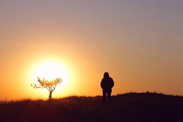 Stark anda flicka stående mot solen vid soluppgången på dagen — Stockfoto