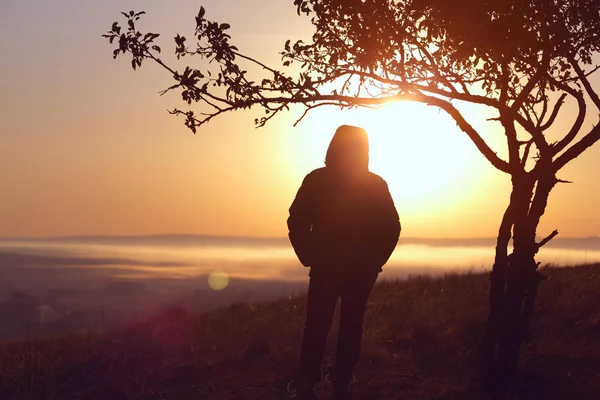 Stark anda flicka stående mot solen vid soluppgången på dagen — Stockfoto