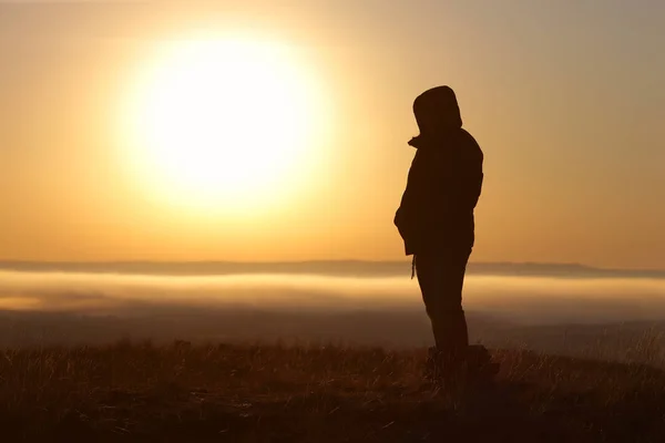 Stark anda flicka stående mot solen vid soluppgången på dagen — Stockfoto