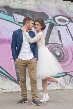 Sadece evli sevgi dolu hipster çift düğün elbise ve açık renkli grafiti duvara şehir ortamda uygun. Mutlu gelin ve damat yürüyüş koşma ve dans. Romantik evli genç aile.