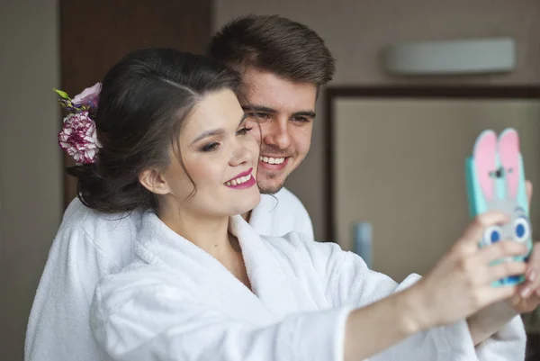 青年和技术。微笑爱对年轻情侣以自拍照时站在酒店房间 — 图库照片