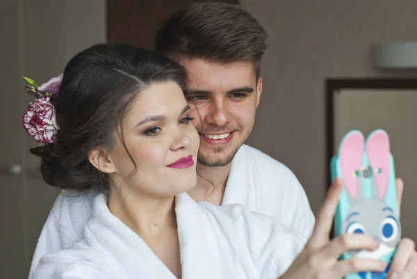 Juventud y tecnología. Joven sonriente pareja amorosa tomando selfie mientras está de pie en la habitación de hotel — Foto de Stock