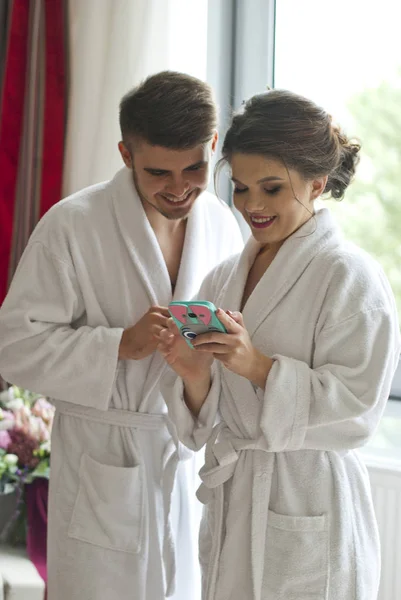 Привлекательная молодая пара смотрит на смартфон в номере отеля — стоковое фото