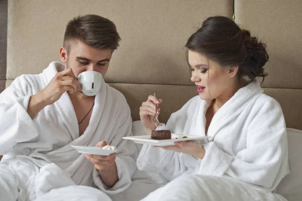 Красивая улыбающаяся молодая пара завтракает в постели — стоковое фото