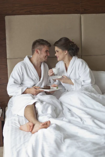 Hermosa joven pareja sonriente desayunando en la cama — Foto de Stock