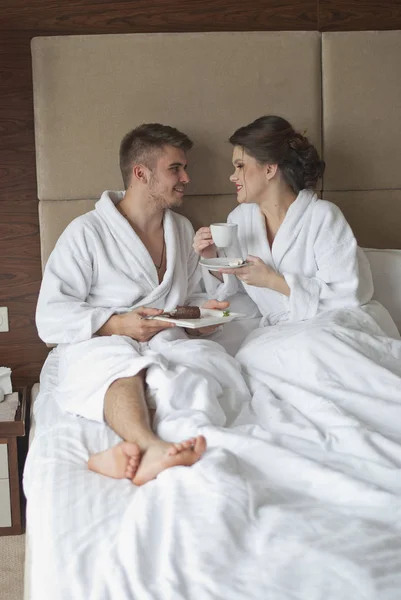 Hermosa joven pareja sonriente desayunando en la cama — Foto de Stock