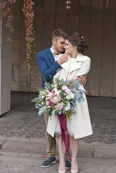 Solo se casó pareja amorosa en vestido de novia y traje al aire libre en el entorno de la ciudad contra la pared. Feliz novia y novio riendo y besándose. Romántica Familia joven casada . —  Fotos de Stock