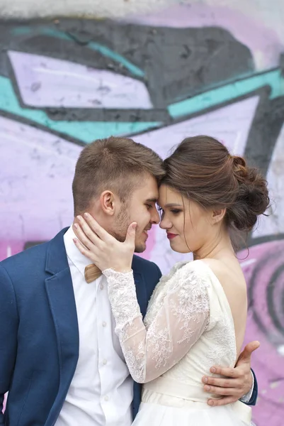 只爱赶时髦的人夫妻在婚礼上穿，适合户外在城市设置七彩涂鸦墙。幸福的新娘和新郎走运行和跳舞。浪漫结婚的年轻家庭. — 图库照片
