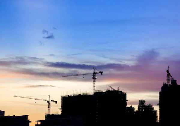 Silhouette-Baustelle mit Kränen gegen bewölkten Himmel — Stockfoto