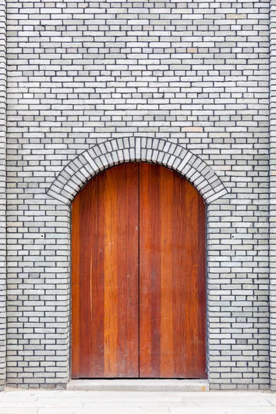 A porta arqueada de madeira tradicional e parede de tijolo, que tem o — Fotografia de Stock