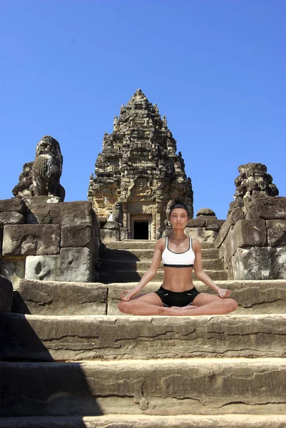 Virtuelle Frau in Yoga-Pose auf einer Stufe eines alten Angkor-Tempels — Stockfoto