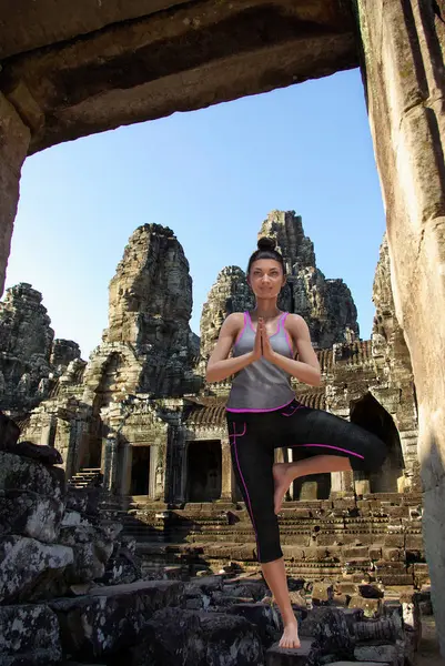 Virtuelle Frau im Yoga-Baum posiert auf Steinen vor einem alten Angkor-Tempel — Stockfoto