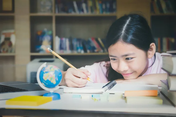 Conceito de educação. Menina lendo e escrevendo na biblioteca . — Fotografia de Stock