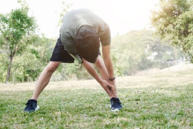 Yeşil Parkı üzerinde egzersiz germe yapmak genç adam.