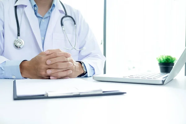 Médico trabalhando com computador portátil e escrevendo sobre papelada — Fotografia de Stock