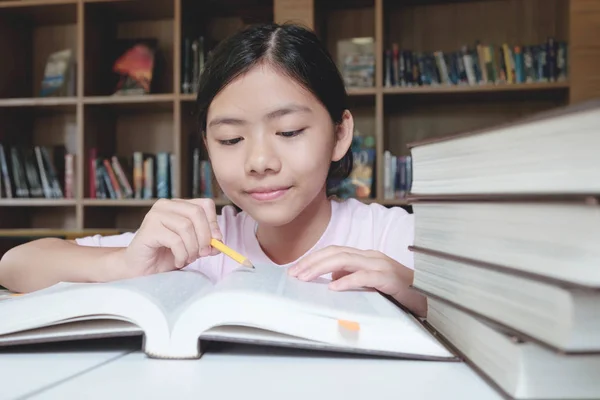 शाळेच्या लायब्ररीत मुलगी वाचन आणि लेखन . — स्टॉक फोटो, इमेज