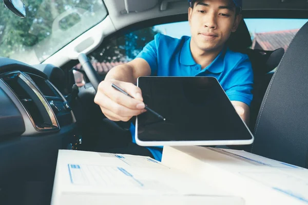 Entregar el hombre sosteniendo la tableta con paquetes en el asiento en el coche . — Foto de Stock