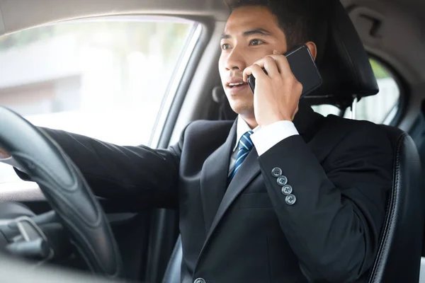 Liikemies puhuu älypuhelimella ajaessaan autoa . — kuvapankkivalokuva
