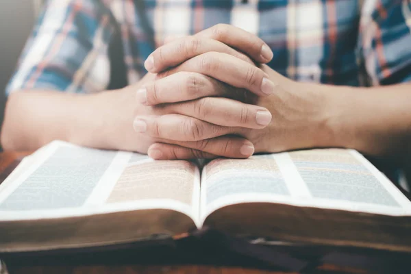 Мужчина молится, руки сжимают вместе на ее Библии . — стоковое фото
