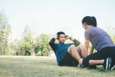 Genç adam ve kadın parkta germe. Genç çift sabah Isınma.