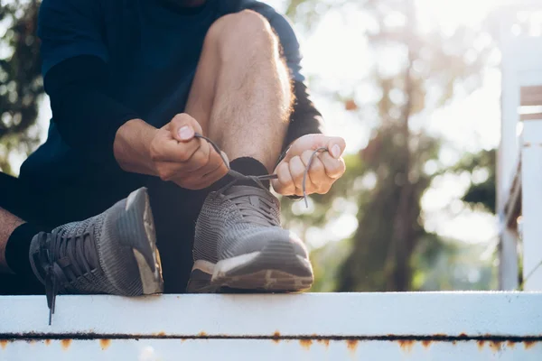 Junger Mann bindet Schnürsenkel. — Stockfoto