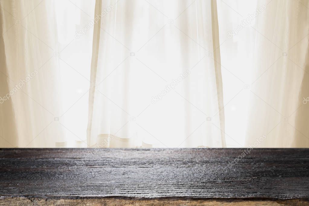 Empty wooden deck table over window curtains background