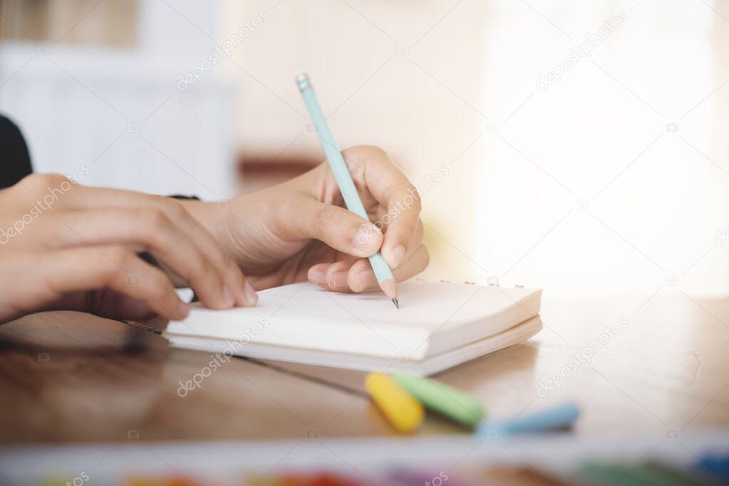 Close up female hands with pen writing on notebook. 