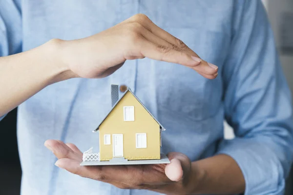 Empresário mão segurar o modelo da casa salvando pequena casa . — Fotografia de Stock