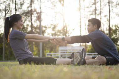 Parkta gerinen genç adam ve kadın. Genç çift egzersizden sonra sakinleşir..
