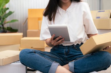 Genç girişimci onun dükkanında online e-ticaret alışverişinde çalışıyor. Müşterilerin siparişlerini kontrol eden ve müşterilere paket teslimatı yapan genç bir online satıcı. Çevrimiçi satış ve çevrimiçi iş e-ticaret kavramı.