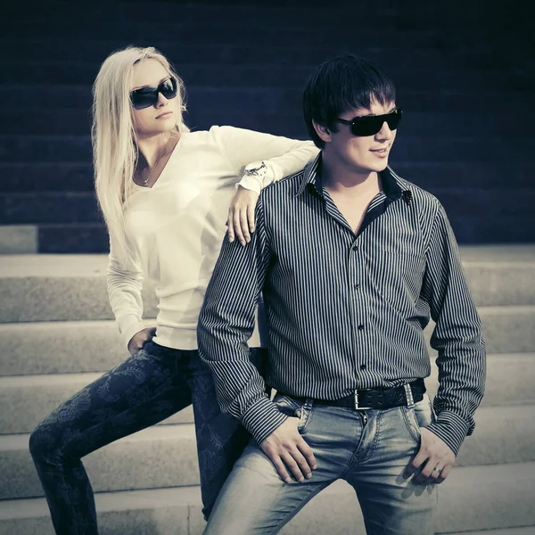 Young fashion couple in sunglasses on the steps