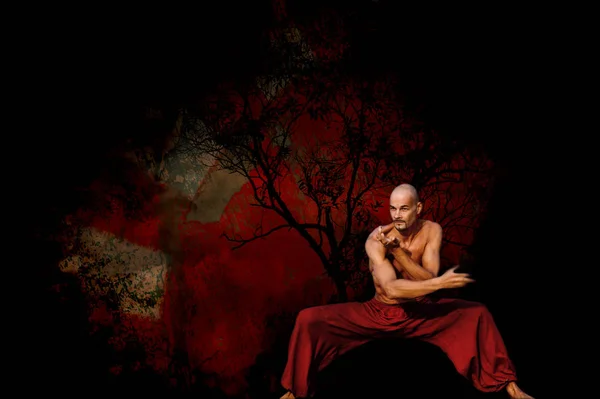 Kampfkünstler in tiefer Haltung mit artistischem roten Hintergrund Stockfoto