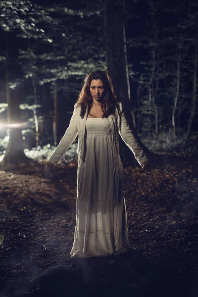 Mujer caminando por el bosque por la noche — Foto de Stock