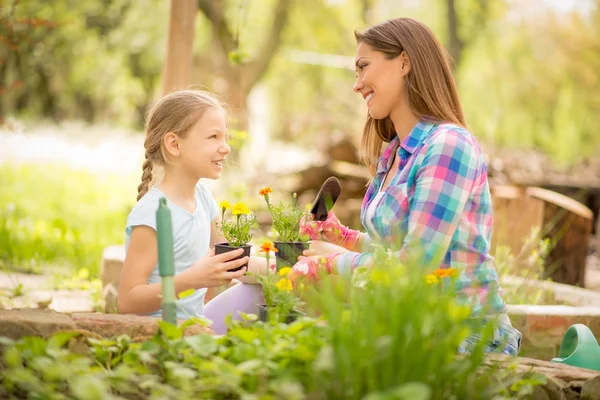 Flicka hjälpa mamman plantera blommor — Stockfoto