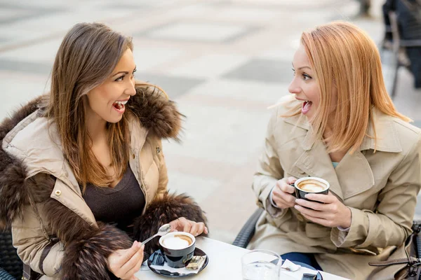 female friends sitting in street cafe