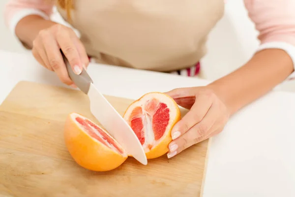 Female hands cutting red grapefruit — Stock Photo, Image