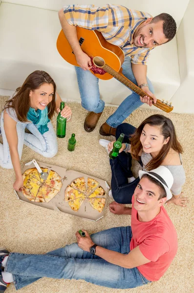 Vrienden feesten met pizza en gitaar — Stockfoto