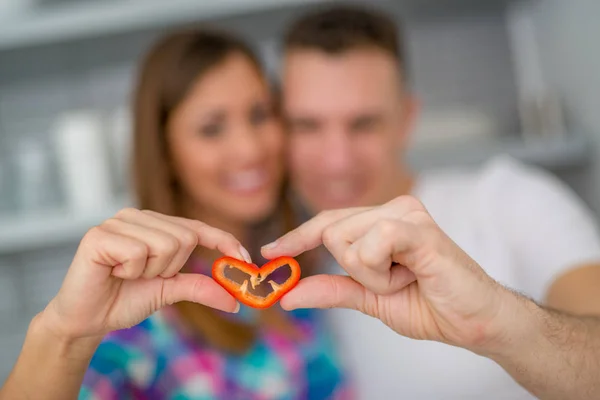 Couple hands holding red paprika in heart shape — Stock Photo, Image