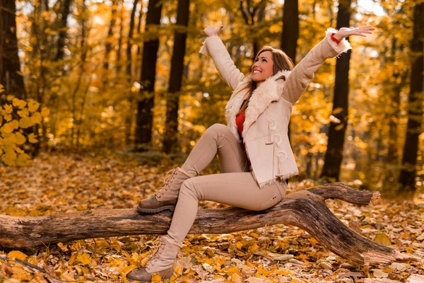 Mujer sentada en el tronco de un árbol en el bosque —  Fotos de Stock