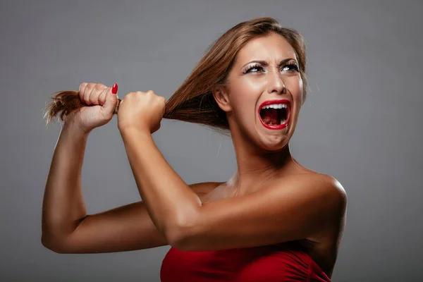 Woman in red dress pulling hair and shouting — Stock Photo, Image