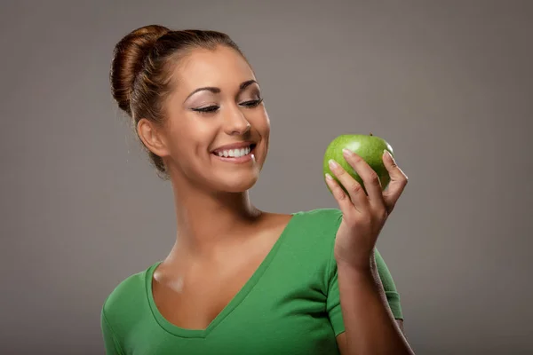 Улыбающаяся женщина держит зеленое яблоко — стоковое фото