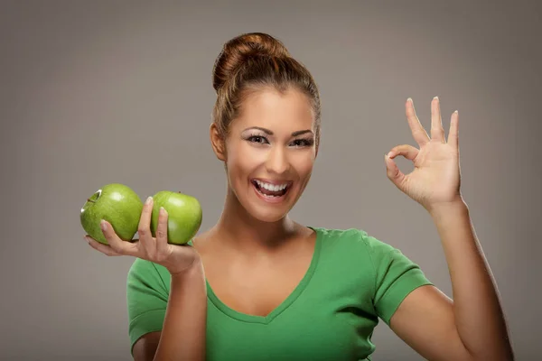 Γυναίκα κρατώντας τα μήλα και δείχνουν εντάξει — Φωτογραφία Αρχείου