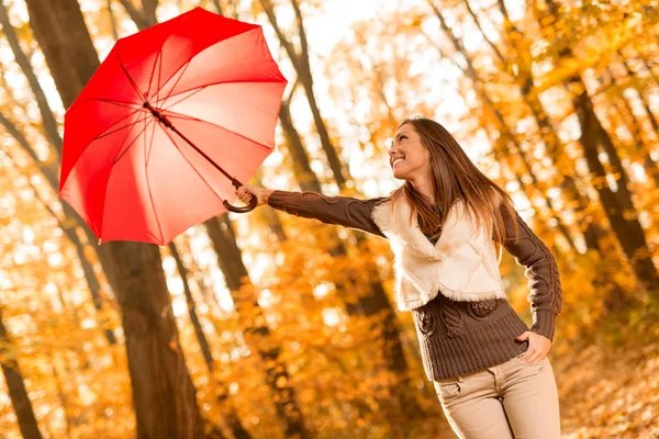 Giovane donna con ombrello rosso nella foresta — Foto Stock