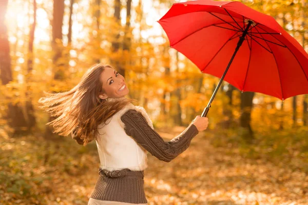 Молода жінка з червоною парасолькою в лісі — стокове фото
