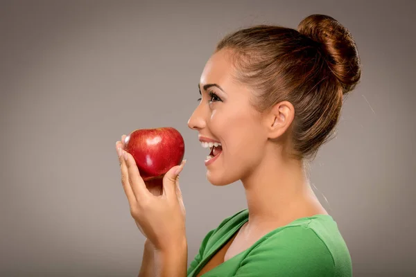 Sonriente mujer mordiendo manzana roja — Foto de Stock